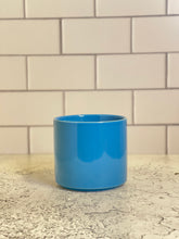 Load image into Gallery viewer, A bright blue cylinder-shaped planter pot with a glossy finish. The planter pot includes a drainage hole.
