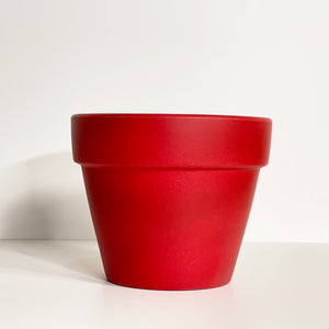 A red terracotta pot with a matte finish. The planter pot includes a drainage hole.