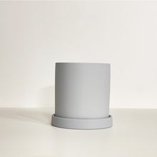 Load image into Gallery viewer, The Cyn is a grey color cylinder-shaped planter pot. The planter pot has a drainage hole and a saucer that helps catch water.
