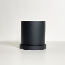 Load image into Gallery viewer, The Cyn is a black cylinder-shaped planter pot. The planter pot has a drainage hole and a saucer that helps catch water.

